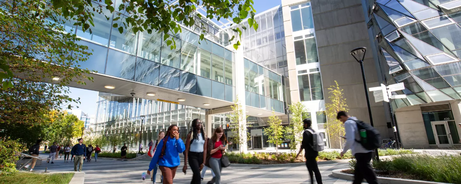 Students walking in campus by glass buildings